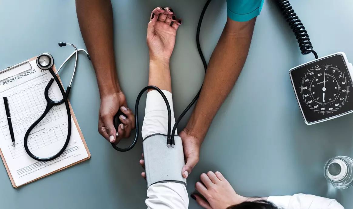 A nurse checks a patient's blood pressure