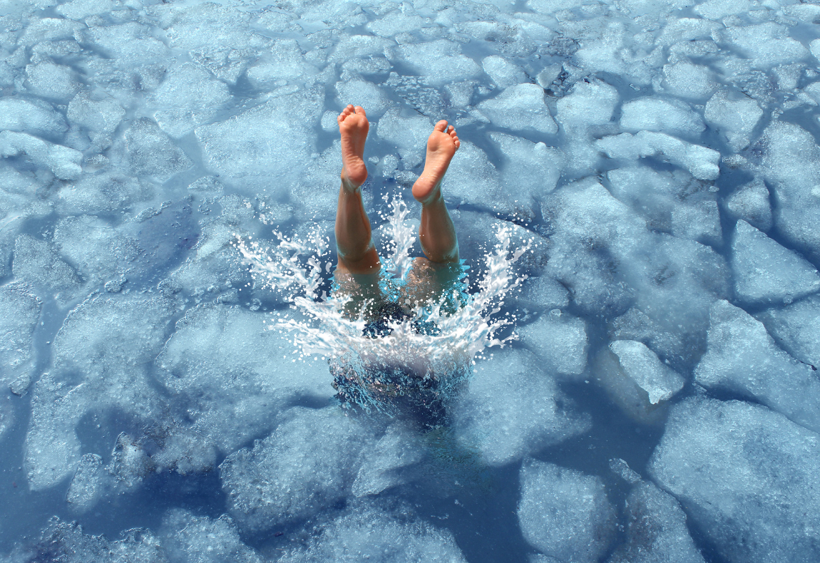 Cool down and cooling off concept as a diver diving into frozen ice water as a symbol for managing hot weather summer heat and refreshing break from a heatwave